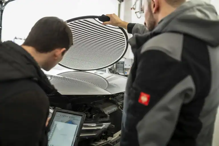 Zwei Mitarbeiter von Schwarz KG prüfen nach den Lack nach der Unfallinstandsetzung