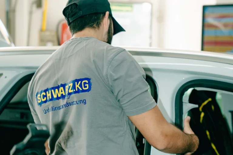 Karosseriebauer arbeitet an einem weißen PKW in einer Karosseriewerkstatt in Schweinfurt