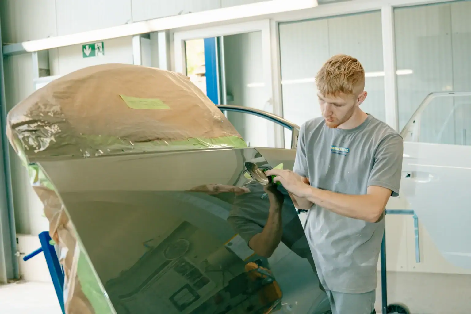 Polierer prüft die Qualität der Lackierung einer Autotür