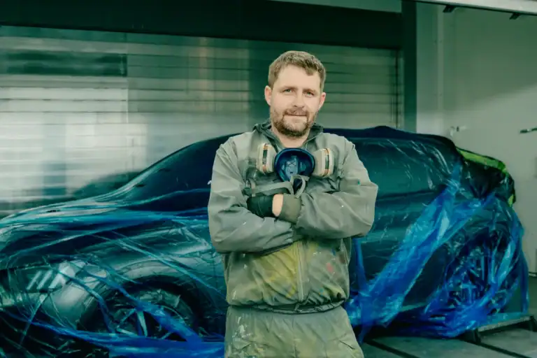 Lackierer von Schwarz.KG vor einem abgeklebten Auto in einer Lackiererei bei Würzburg
